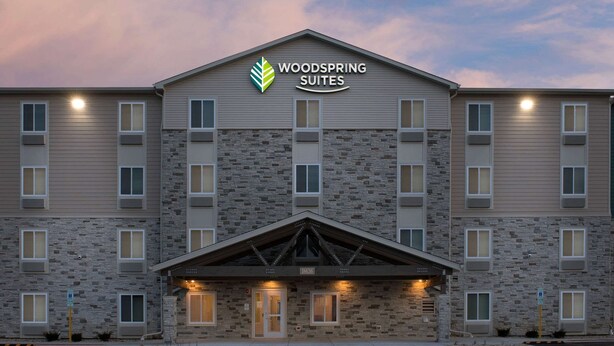 Un hotel con facciata in pietra, diverse finestre e un cartello con la scritta "Woodspring Suites".
