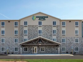 Un hotel Woodspring Suites con fachada de piedra, múltiples ventanas y entrada cubierta.