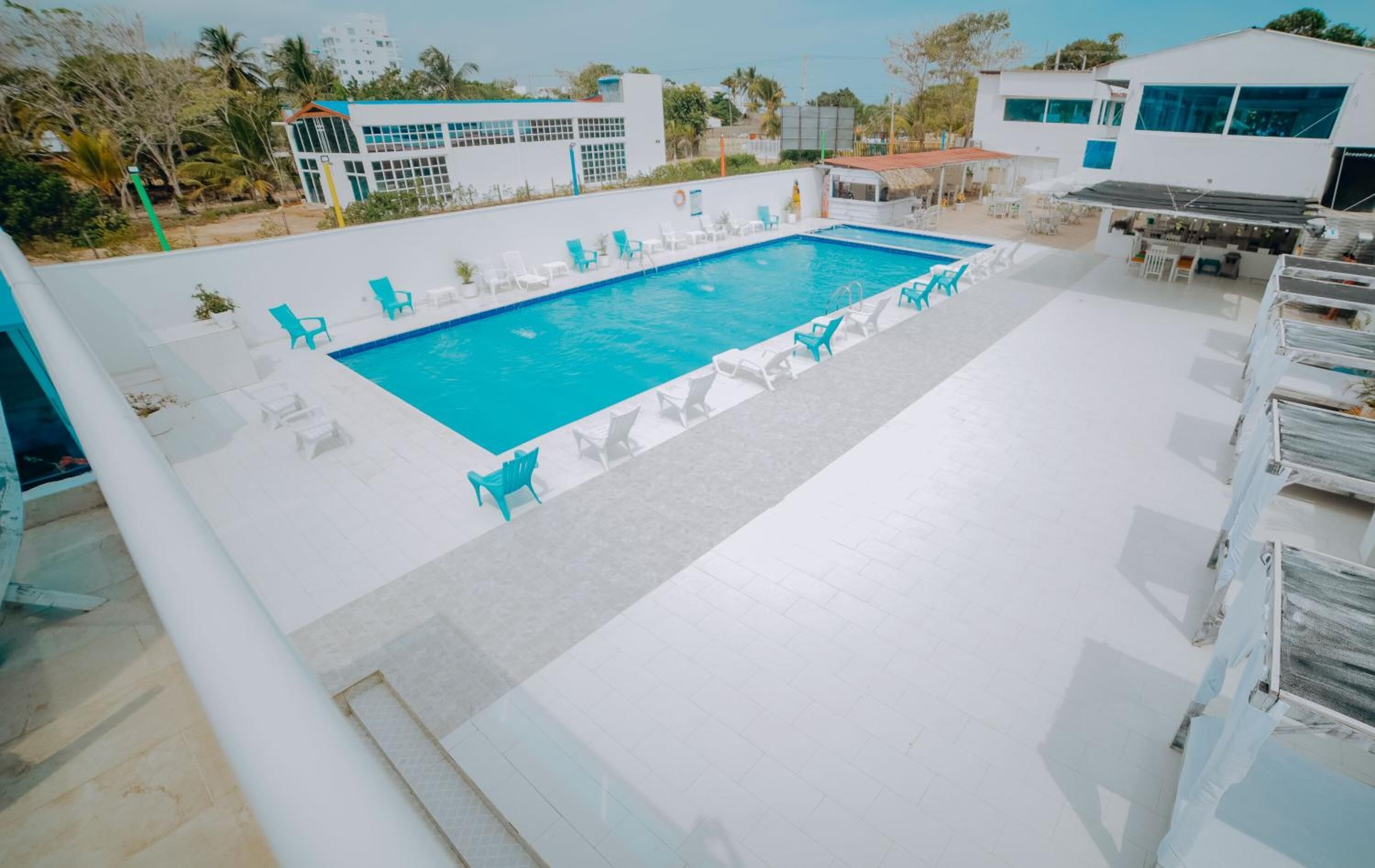 A swimming pool with blue chairs and a white building in the background.
