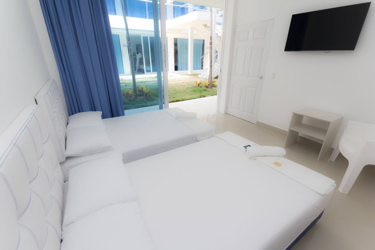 Een moderne hotelkamer met een groot bed, een aan de muur bevestigde televisie en uitzicht op het buitengebied.