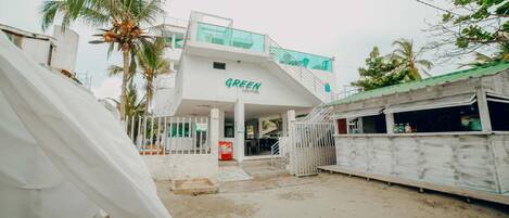 Un edificio con un letrero que dice "GREEN" y un espacio al aire libre cubierto con una escalera que sube a un nivel superior.