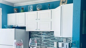 Une cuisine moderne avec des meubles blancs, un plan de travail en granit et un pare-feu décoré de carreaux bleus et verts.