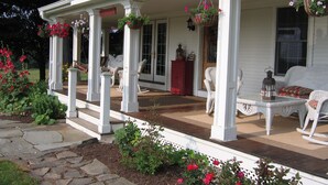 A white porch with white wicker furniture, stone steps, and hanging flower baskets. - Maple Shade Bed & Breakfast  (Stillwater)