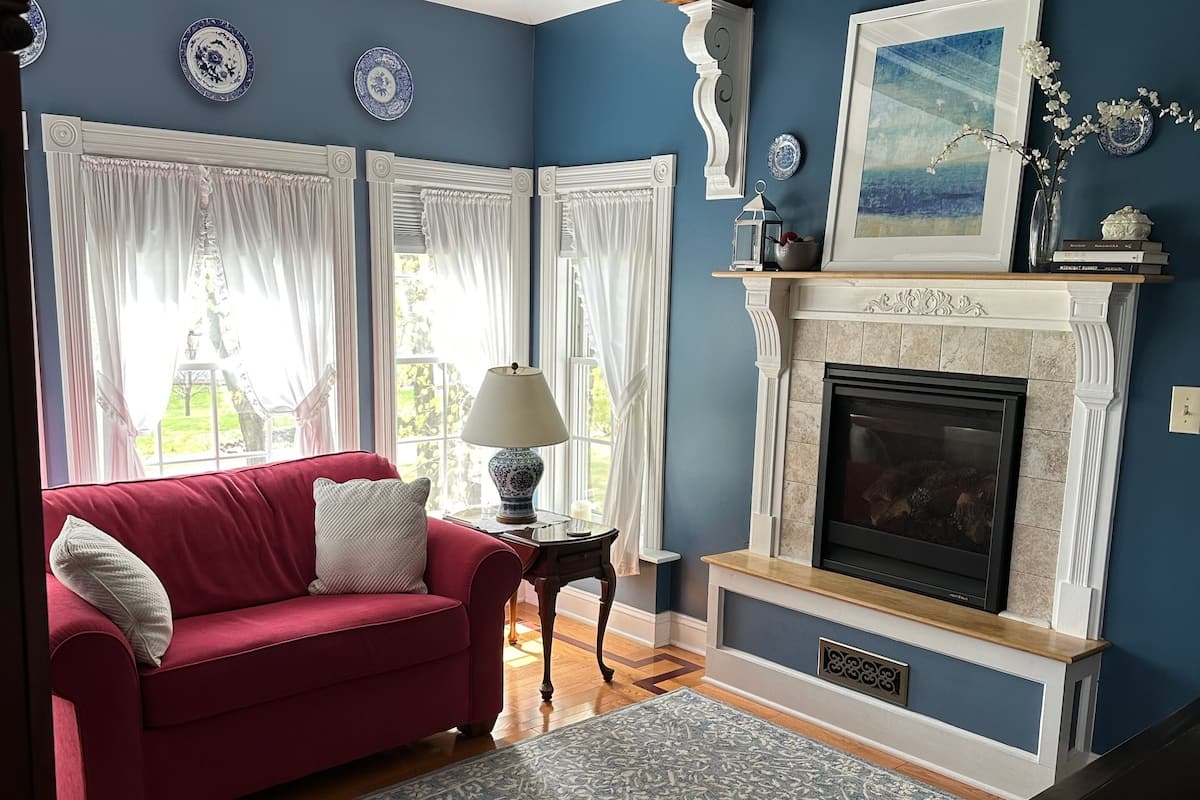 A room with a red sofa, a fireplace, and a blue wall.