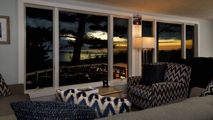 A living room with large windows, a sofa, a chair, and a lamp. - Looking Glass Beachfront Inn (Grand Haven)