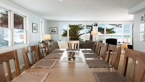 A dining room with a long wooden table set for six, surrounded by wooden chairs. - Looking Glass Beachfront Inn (Grand Haven)