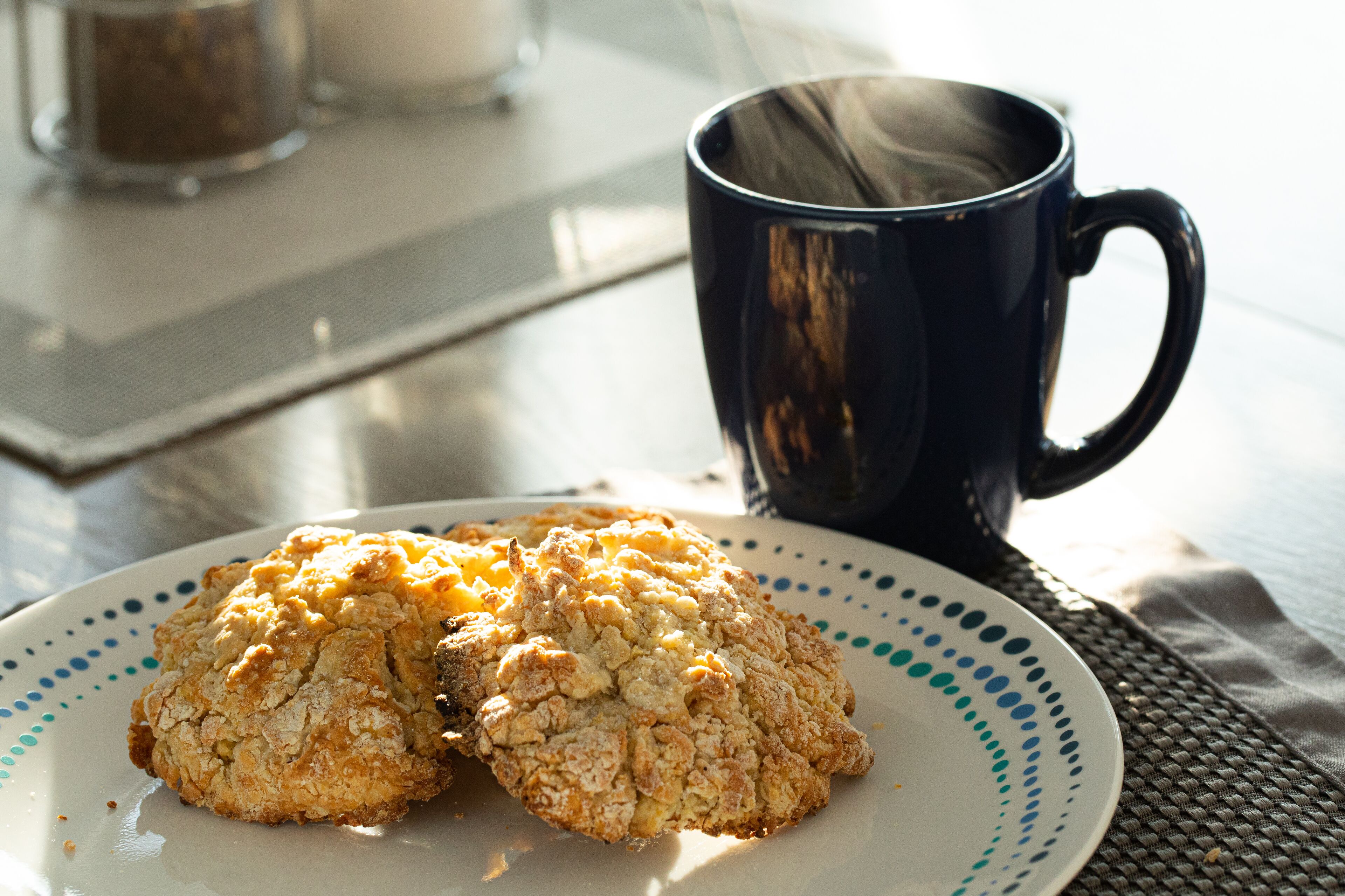 A plate with two cookies and a black mug on a table.