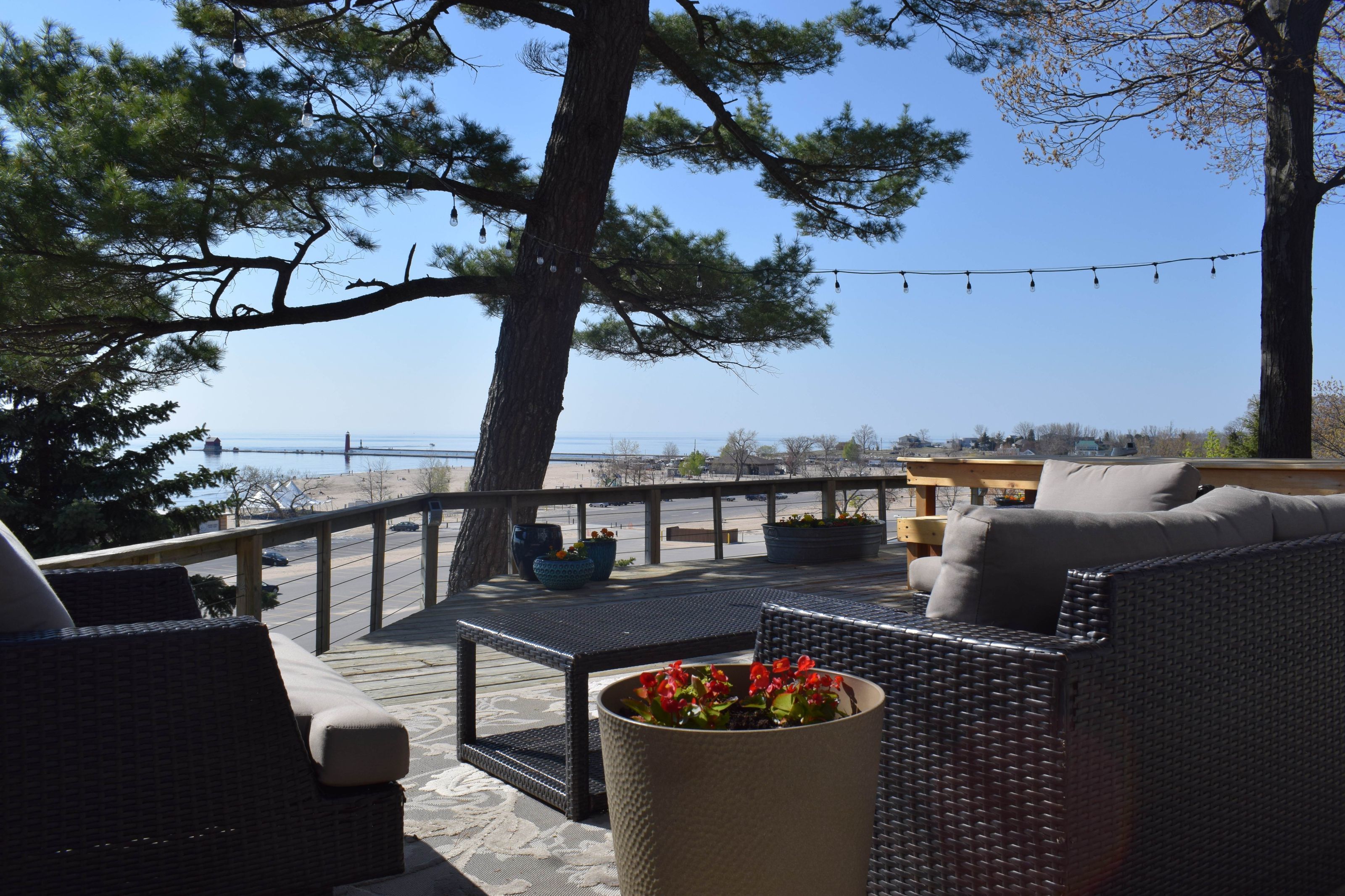 A deck with wicker furniture, a table, and potted plants.