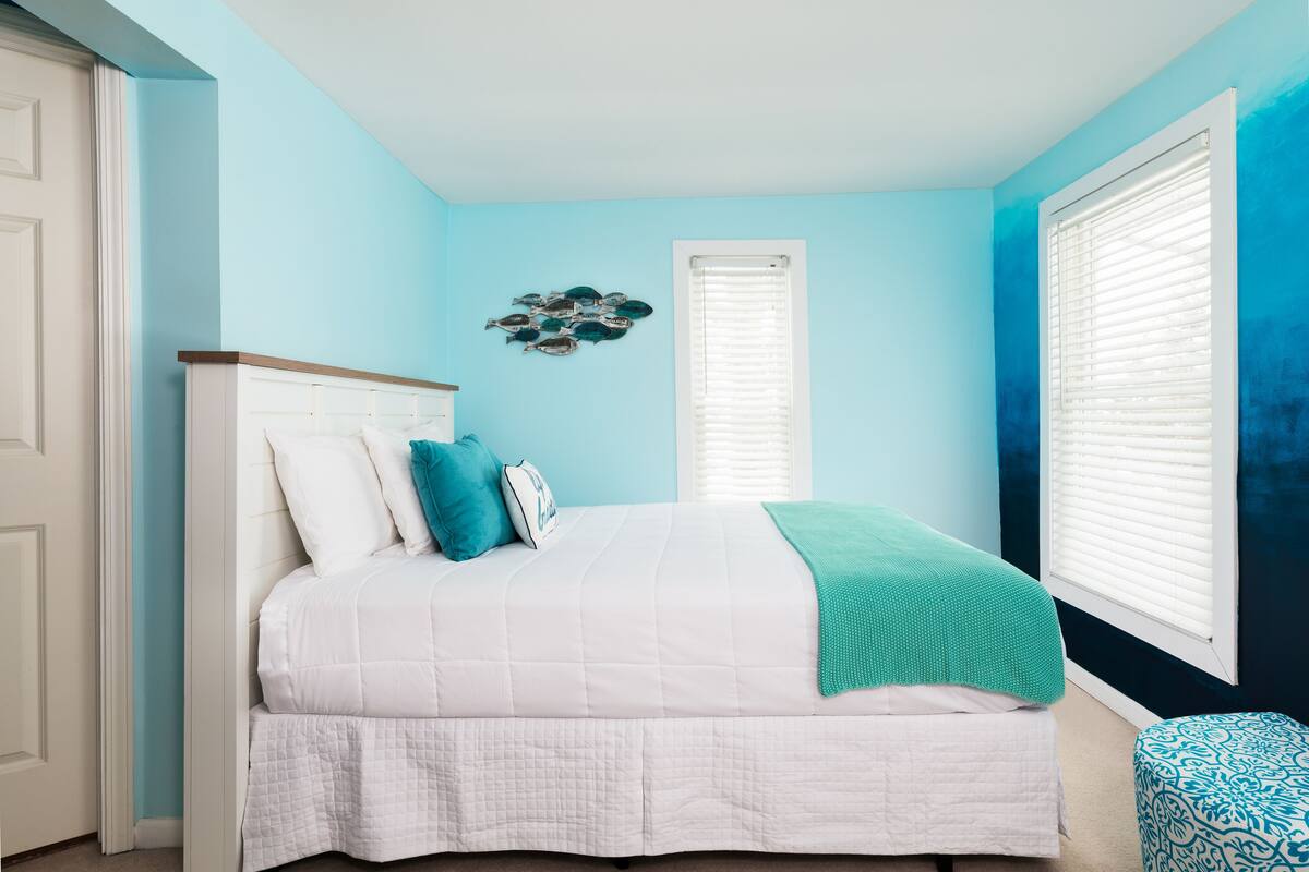 A bedroom with a bed, a window with blinds, and a wall decoration.