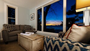 A living room with a sofa, a patterned ottoman, and a wooden coffee table. - Looking Glass Beachfront Inn (Grand Haven)