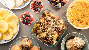 Variedad de opciones para el desayuno, como quiche, ensaladas de frutas, muffins y tostadas.