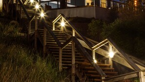A two-story house with a staircase leading to a balcony, surrounded by tall grass and trees. - Looking Glass Beachfront Inn (Grand Haven)