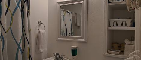A bathroom with a sink, mirror, and vanity.