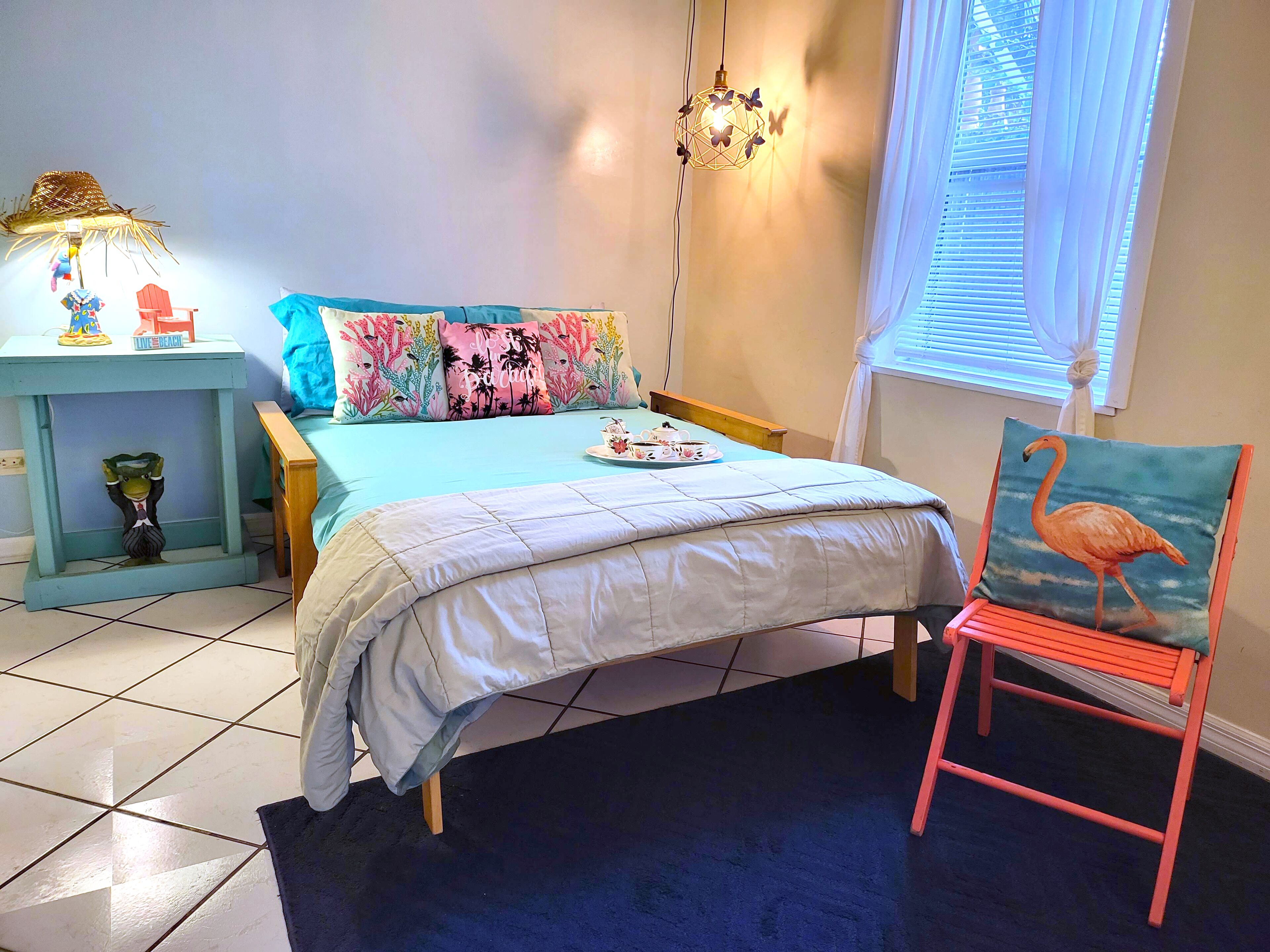 A bedroom with a bed, a nightstand, a chair, and a window with curtains.