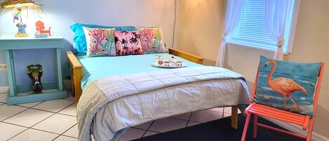A bedroom with a bed, a nightstand, a chair, and a window with curtains.