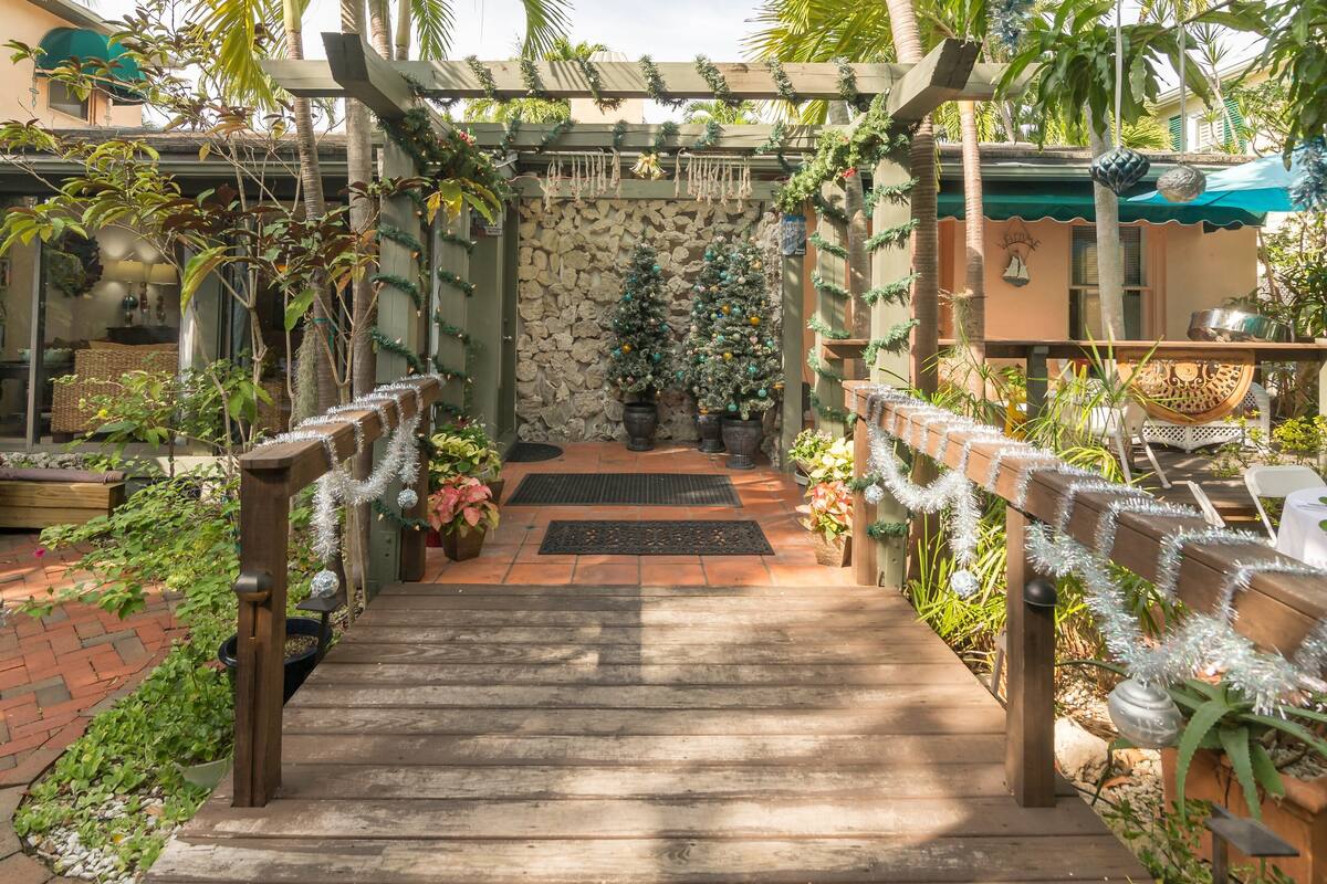 A wooden pathway leading to a stone wall with two decorated Christmas trees.