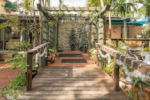 Un sendero de madera que lleva a un muro de piedra con dos árboles de Navidad decorados.