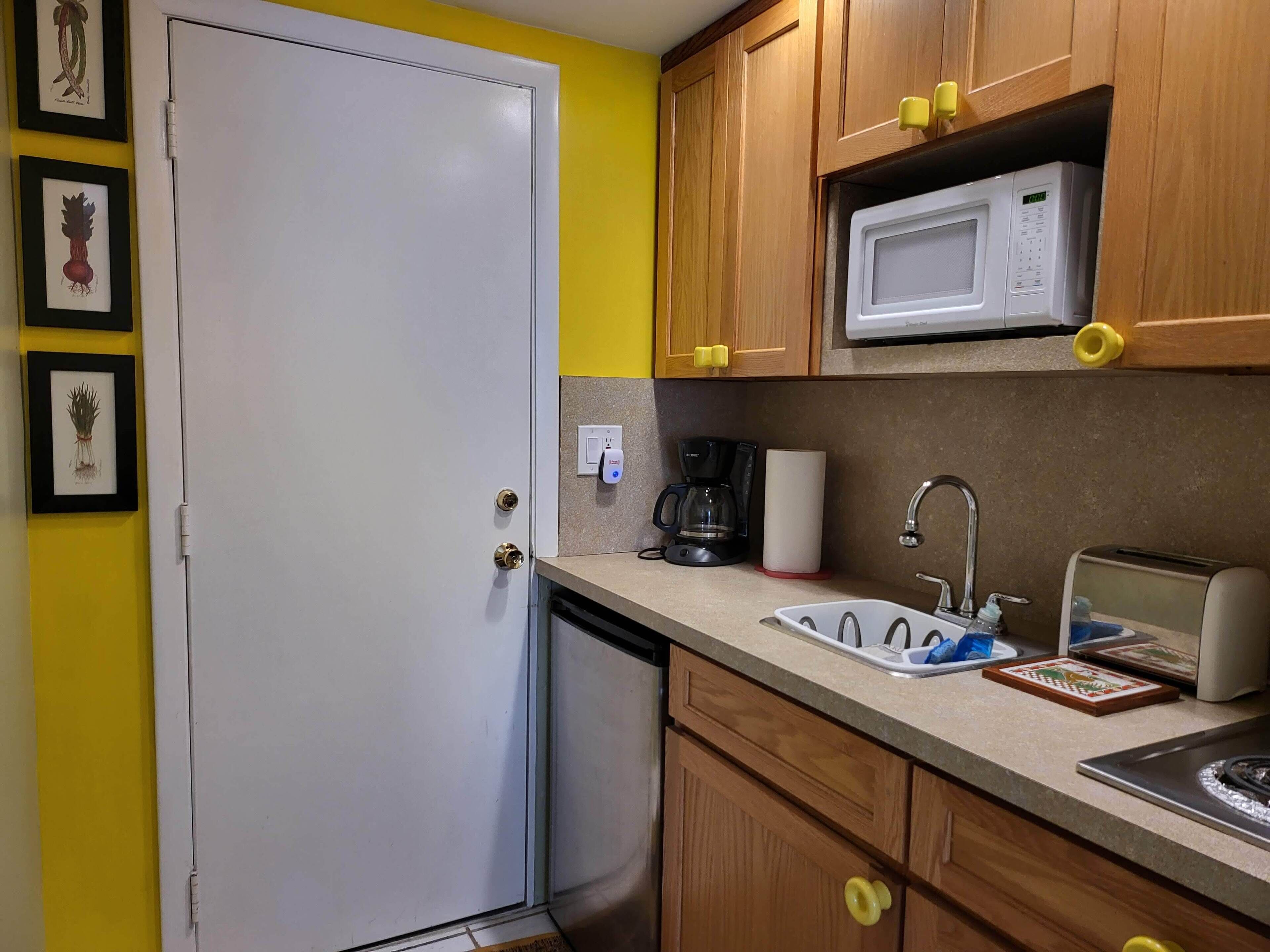 Una cocina compacta equipada con microondas, cafetera y tostadora.