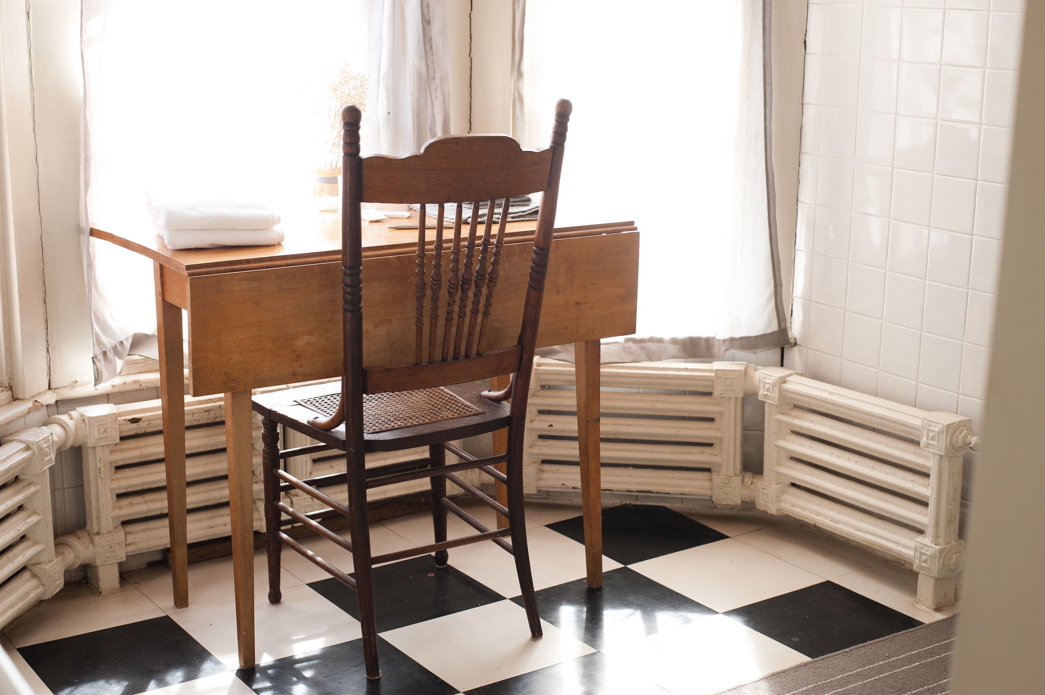 A corner room with a wooden chair, a table, and a radiator.
