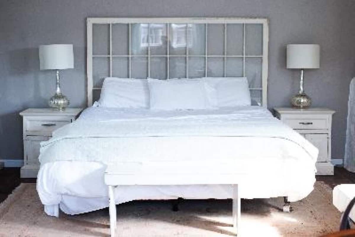 A white bed with a wooden headboard in a bedroom.