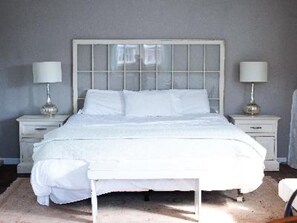 Una cama blanca con cabecera de madera en un dormitorio.