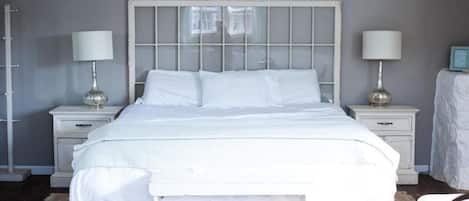 A neatly made bed with a white headboard and footboard, flanked by two bedside tables with lamps.