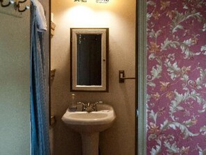A bathroom with a sink and mirror, a towel rack, and floral wallpaper. - Ash Mill Farm Bed & Breakfast (Holicong)