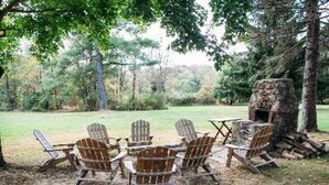 A rustic outdoor seating area with Adirondack chairs and a stone fire pit. - Ash Mill Farm Bed & Breakfast (Holicong)