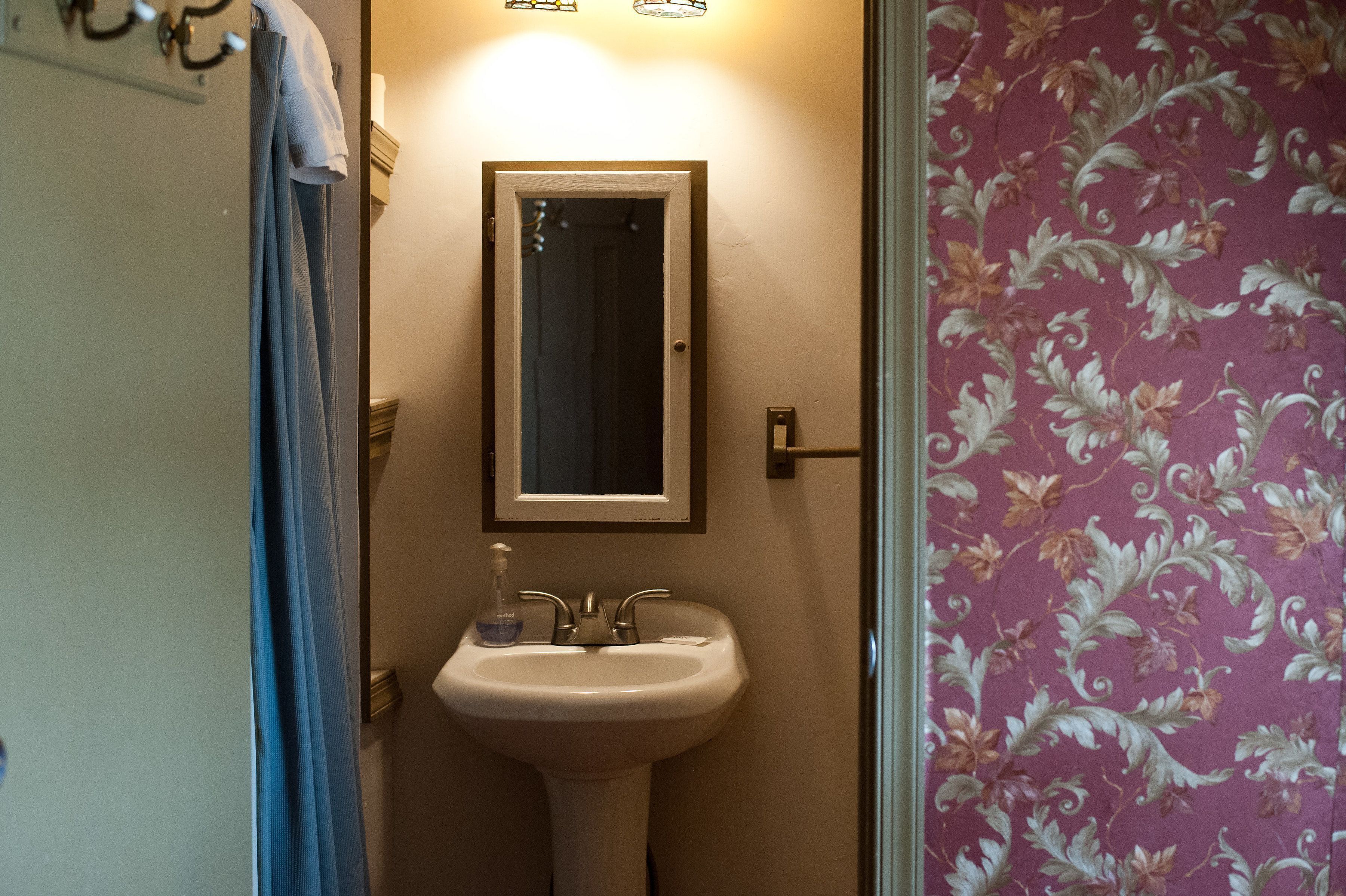 A bathroom with a sink, a mirror, and a door.