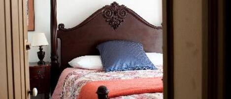 A bedroom with a wooden bed, a nightstand, and a lamp.