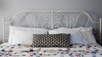 A bed with a white metal frame, white pillows, and a quilt with a patchwork design.