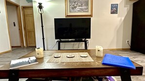 Una sala de estar con una mesa de centro de madera, un televisor de pantalla plana y un cuadro en la pared.