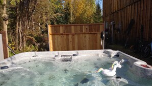Un jacuzzi con un flotador con forma de unicornio, rodeado de una cerca de madera y árboles.
