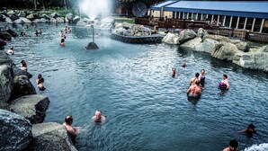 Una fuente termal natural con gente nadando y relajándose.