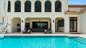 A swimming pool with a sun terrace, lounge chairs, and a covered seating area. - NEW FURNITURE Aug 2026 | Movie Theater & Games Room | Golf Course Views (Kissimmee)