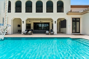 A swimming pool with a sun terrace, lounge chairs, and a covered seating area. - NEW FURNITURE Aug 2026 | Movie Theater & Games Room | Golf Course Views (Kissimmee)