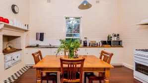 A kitchen with a wooden table, chairs, a hanging light, a stove, and a window.