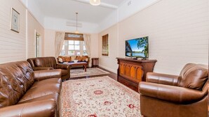 A living room with leather sofas, a wooden cabinet, and a television on the wall.