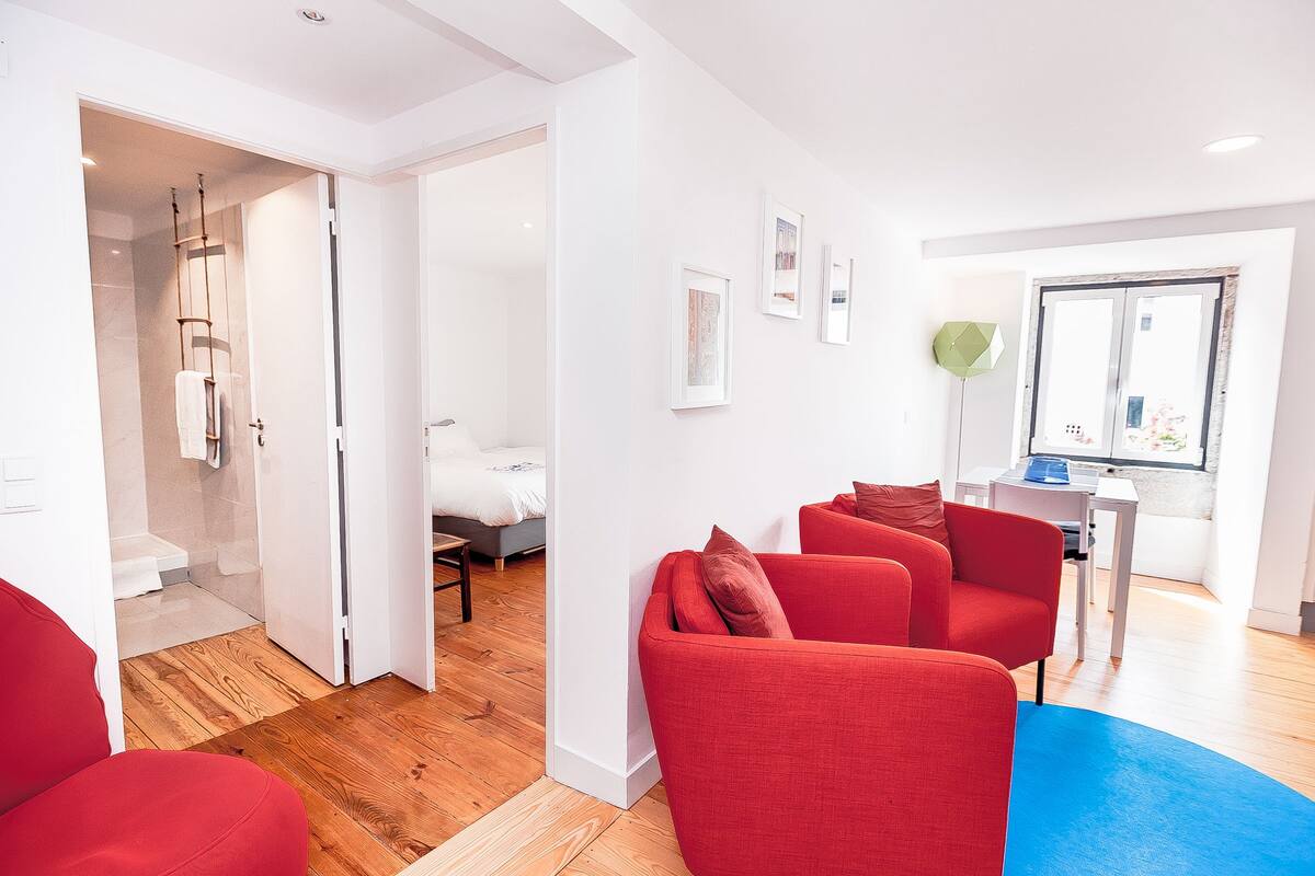 Una sala de estar moderna con sofás rojos, una alfombra azul y piso de madera.