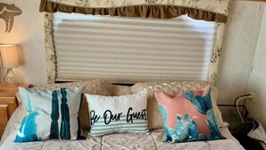 A bed with a beige quilt and three decorative pillows. - NW Tucson - Roomy 20 Foot RV Nestled On A 3 Acre Property Sleeps 4 (Tucson)