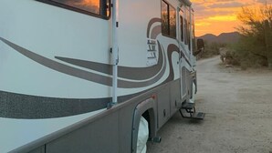 A recreational vehicle parked on a dirt road with a sunset in the background. - NW Tucson - Roomy 20 Foot RV Nestled On A 3 Acre Property Sleeps 4 (Tucson)