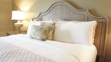 A neatly made bed with a quilted white bedspread, two pillows, and a wooden headboard.
