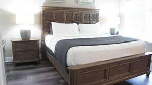 A bedroom with a wooden bed, two bedside tables, and a window with blinds. - Magnolia Creek Lodge (Cottonwood)