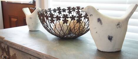 A kitchen counter with a decorative metal basket and two ceramic pitchers.