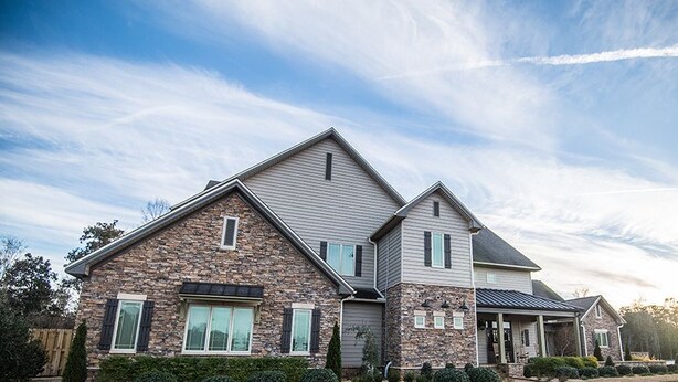 A two-story house with a stone facade, a gabled roof, and a front porch. - Magnolia Creek Lodge (Cottonwood)