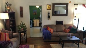 A living room with a sofa, a coffee table, and a lamp. There is a small table with a plant and a globe. The room has wooden flooring and a rug. - Downtown Casa Bonita (Flagstaff)