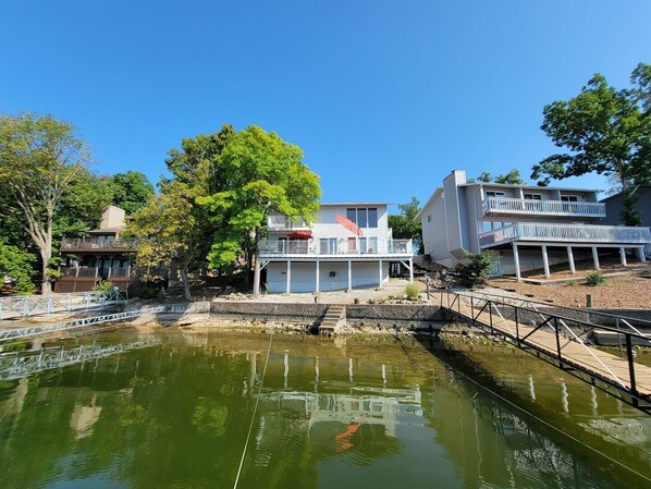 A waterfront property with a dock, a bridge, and a house with a balcony.