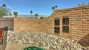 A stone patio with a brick wall, palm trees, and a mountain view. - East Tucson Home w/ Backyard, Patio & Fire Pit (Tucson)