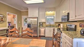 A modern kitchen with white cabinets, stainless steel appliances, and a granite countertop.