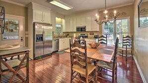 A kitchen with white cabinets, a stainless steel refrigerator, a microwave, and a dining area with wooden chairs and a table. - Lake Keowee Escape w/ Dock, Deck & Lake Access! (Six Mile)